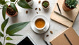 A flat lay of a workspace on a white marble surface features a cup of warm tea on a saucer at the center. Surrounding it are tan notebooks, metallic pens, and a black pencil. Potted green plants and scattered seeds add a natural touch. A tablet with a black screen rests at the bottom corner. The soft lighting and earthy tones create a balanced and clean composition. Ai generated. Photography style.