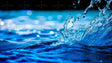 The image captures a close-up of water in motion, with a detailed splash rising from the surface. The deep blue tones contrast with the bright highlights, enhancing the texture of the liquid. Tiny water droplets are suspended in the air, reflecting light. The background features a soft bokeh effect with blurred circles of light, adding depth and a smooth transition from the sharp details in the foreground. Ai generated. Photography style.