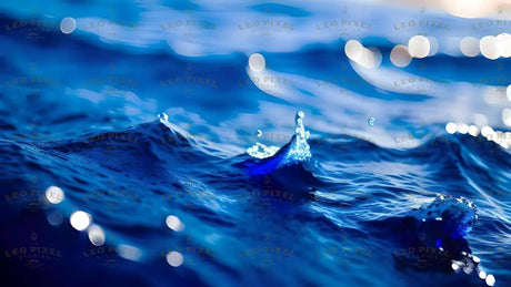 The image captures a close-up of deep blue water in motion, with small peaks and splashes highlighted by bright reflections. The surface is textured with fine waves, and a single droplet rises above the crest. Soft, glowing bokeh lights in the background add depth, blending with the cool blue tones. The contrast between light and shadow enhances the details of the rippling water. Ai generated. Photography style.