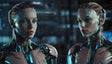 In a cutting-edge lab, two humanoid digital twins with sleek metallic exteriors and glowing blue circuitry stand face-to-face. Their intricate designs blend human-like features with advanced technology, set against a high-tech backdrop of illuminated interfaces and machinery, symbolizing the pinnacle of AI and robotics innovation. Ai generated image.