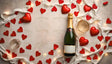 A flat lay features a champagne bottle with a golden neck, a filled glass, and scattered red hearts on a textured white background. White fabric ribbon intertwined with warm string lights enhances the romantic ambiance, while glossy red hearts add vibrancy. The arrangement is simple yet elegant, creating a sophisticated and celebratory feel. Ai generated. Flat lay photography style.