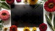 Flat lay image on a white surface featuring a black rectangular paper at the center. Surrounding it are vibrant flowers including red, yellow, pink, and white daisies, along with lush green leaves and long grass-like blades. The flowers vary in texture and size, creating a balanced and colorful border. The dark paper contrasts with the bright petals, enhancing the vividness of the arrangement. Ai generated. Photography style.