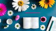 A blue background features an open blank notebook in the center, surrounded by scattered flowers in white, pink, and yellow. A pink pencil is positioned above the notebook. To the right, a white document with a teal pen rests on the surface. A small white cup sits on the left, with a loose flower beside it. The mix of bright flowers and stationery creates a clean and colorful composition. Ai generated. Photography style.