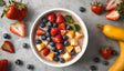 A vibrant smoothie bowl garnished with fresh strawberries, blueberries, and pineapple chunks, accented with a sprig of mint. Surrounding the bowl are whole and sliced strawberries, blueberries, and a ripe banana, arranged on a smooth, neutral surface. The colorful presentation highlights the fresh, natural ingredients and creates an inviting, nutritious aesthetic. Ai generated. Photography style.