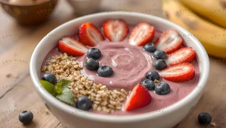 A white bowl filled with creamy pink smoothie is topped with neatly arranged slices of strawberries, plump blueberries, and crunchy granola clusters. A sprig of fresh green basil adds a pop of color, while bananas and additional berries are scattered in the blurred background on a wooden table, creating a wholesome and appetizing scene. Ai generated. Photography style.