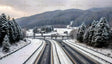 A winding highway cuts through a serene snowy valley surrounded by tall, frosted evergreens and rolling hills. Cozy mountain cottages dot the landscape, evoking a peaceful winter charm. The contrast of the modern road with the tranquil village and towering forest creates a harmonious blend of nature and progress, perfect for a scenic winter journey. Ai generated image.