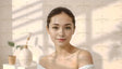 A young woman with smooth skin and neatly tied back hair looks directly at the camera, her lips forming a gentle smile. She is illuminated by soft natural light casting delicate shadows. Behind her, a white table holds a small potted plant and a minimalist vase, enhancing the serene and elegant setting. Ai generated. Photography style.