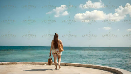 A woman with long, flowing hair walks barefoot on a smooth stone path, carrying a tan handbag and a smaller bag in each hand. She wears light floral-patterned shorts and a simple top. The bright turquoise sea stretches endlessly ahead under a clear blue sky dotted with a few soft white clouds. The scene is serene, with the ocean and sky blending at the horizon. Ai generated. Photography style.