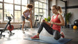 Two women are exercising in a gym with large windows allowing natural light to fill the space. One woman, in a red tank top and black leggings, kneels on a yoga mat with focused determination. Behind her, another woman in a light purple tank top and gray shorts performs a workout move. A stationary bike, greenery, and gym equipment decorate the bright and organized space. Ai generated. Photography style.